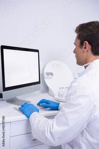 Side view of dentist working on computer