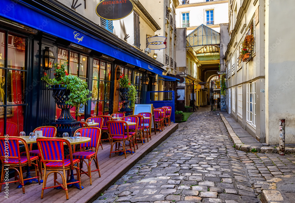 Obraz premium Przytulna ulica z stołami kawiarni w Paryżu, Francja