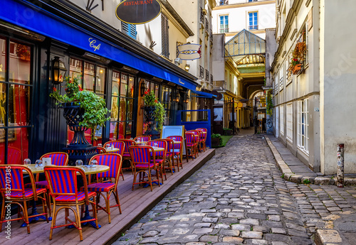 Fototapeta Przytulna ulica ze stolikami kawiarni w Paryżu, Francja