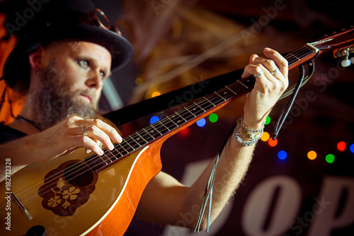  eccentric man in a hat performs at a music bar. plays Irish bouzouki (girar) blurred motion