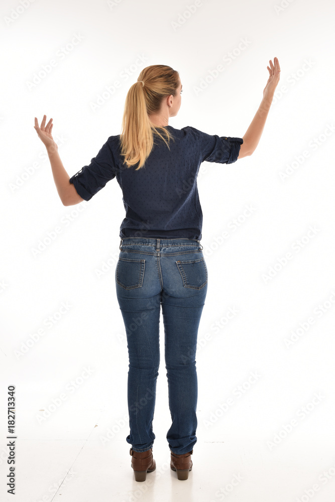 Full length portrait of a girl wearing simple blue shirt and jeans, standing pose facing away on a white background. Full length portrait of a girl wearing simple blue shirt and jeans, standing pose facing away on a white background.