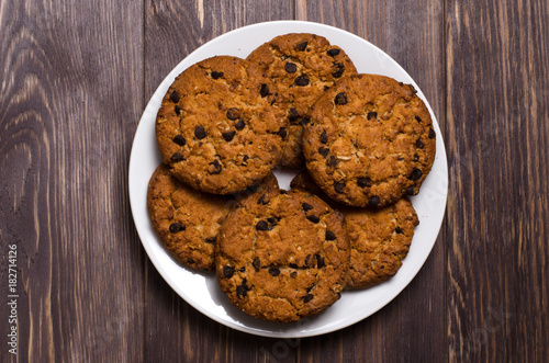 Homemade oatmeal cookies on a white plate. Wooden background