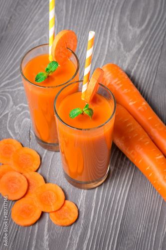 Carrot smoothie with ingredients on gray background