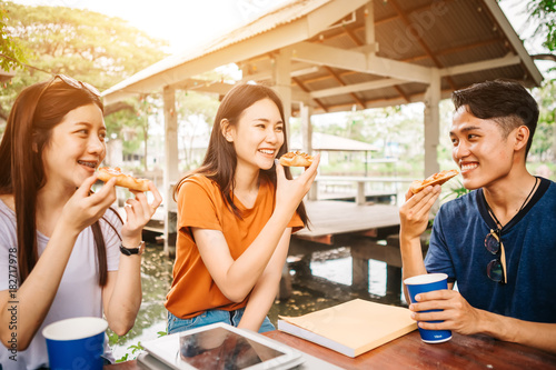 Tablou pe pânză Asian students eating eating the pizza together in breaking time early next study class having fun and enjoy party, Italian food slice with cheese delicious at university outdoor