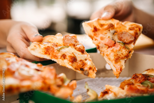 Asian students eating eating the pizza together in breaking time early next study class having fun and enjoy party, Italian food slice with cheese delicious at university outdoor.