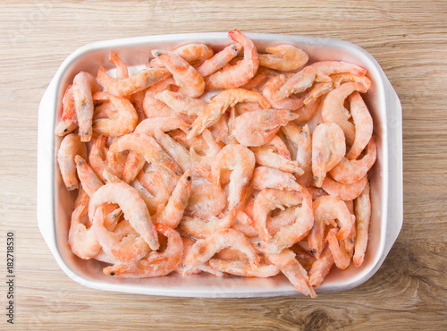 Frozen shrimps in ice. Many royal shrimps on an iron tray.