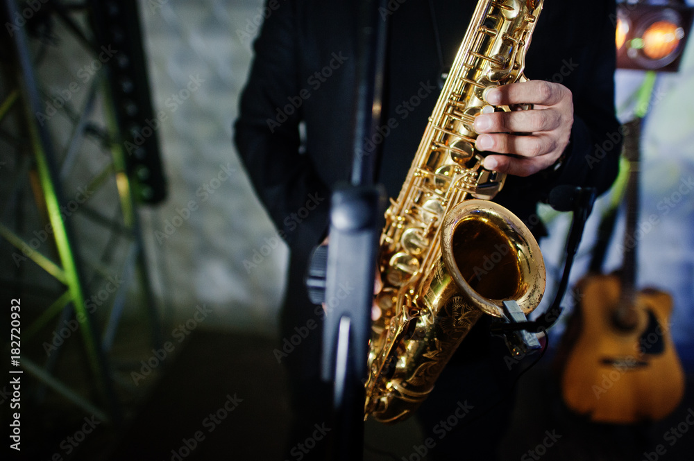 Fototapeta premium Musicial music live band performing on a stage with different lights. Saxophonist plays.
