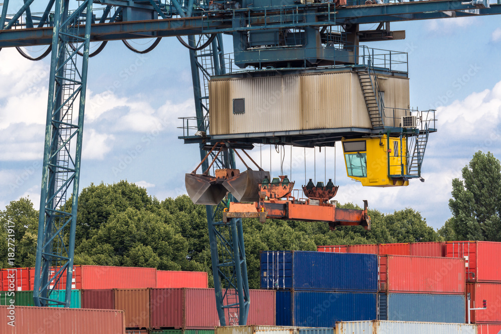 Lastenkran positioniert sich über gestapelten Containern im ...