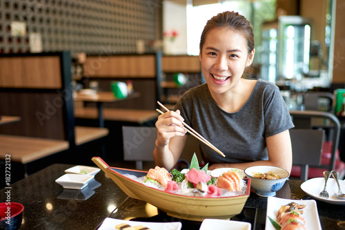 Beautiful asian woman eating sashimi, Japanese food.