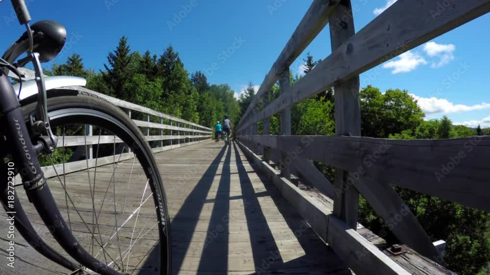 People riding their bikes over wood bridge in forest People riding their bikes over wood bridge in forest
