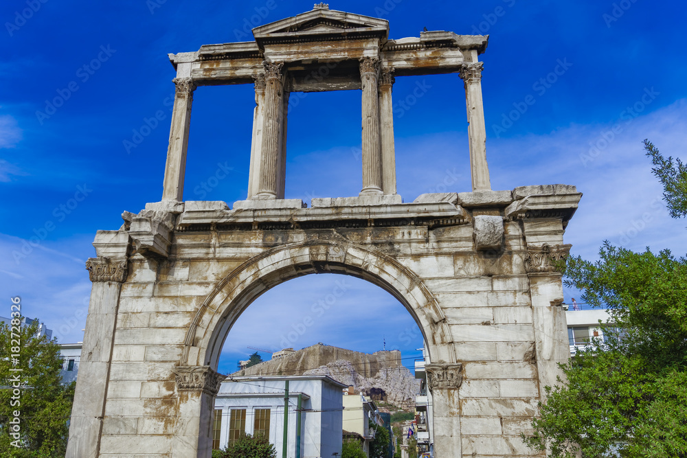 Athens, Greece Hadrian's Arch day view. Ancient marble gateway with Corinthian columns and background view of Athens Acropolis.