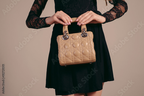Fashionable woman with a brown bag in her hands and black evening dress photo