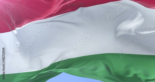 Flag of Hungary waving at wind in slow in blue sky, loop photo