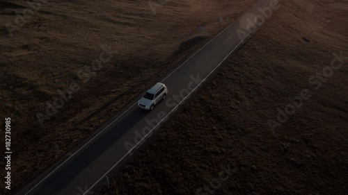 Beautiful aerial view of car driving along Icelandic road with beautiful sunrise in background