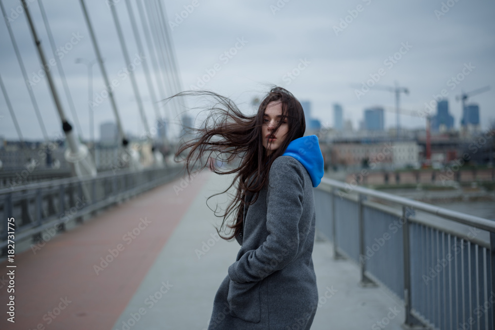 View on the bridge with young woman walking back during the windy weather in Warsaw city, Poland
