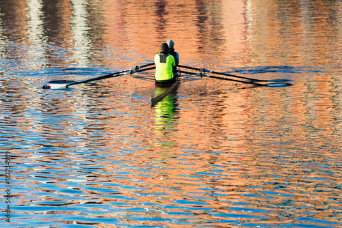 competitive rowers in early morning sun with orange relfection on water