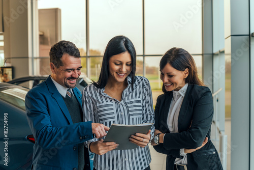 Car dealer showing contract to his customers.