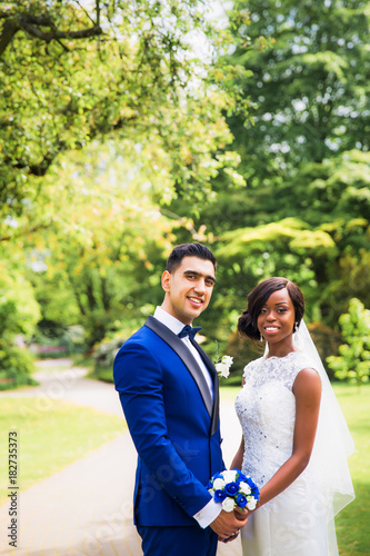 The young happy newlyweds standing in the park and holding hands each other