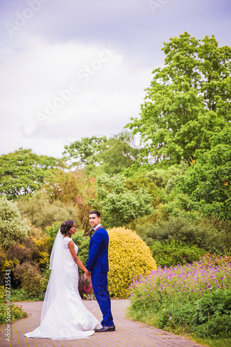 The young romantic newlyweds standing in the park and holding hands each other