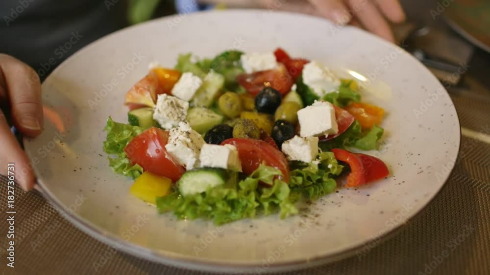 Woman eating salad in an indoor cafe, close up on a plate. Woman eating salad in an indoor cafe, close up on a plate.