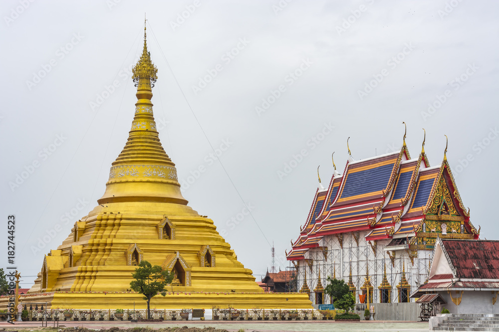Fototapeta premium a large golden pagoda with a smaller, white building next to it. Both buildings have elaborate, ornate roofs.