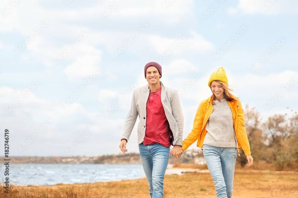 Young couple walking near river on autumn day