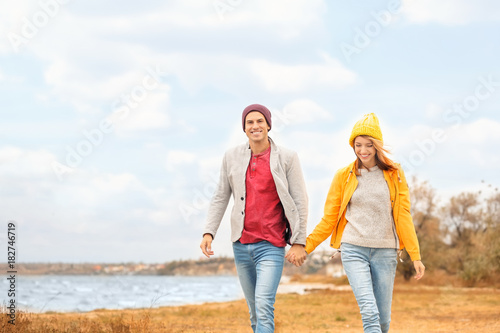 Young couple walking near river on autumn day © Africa Studio