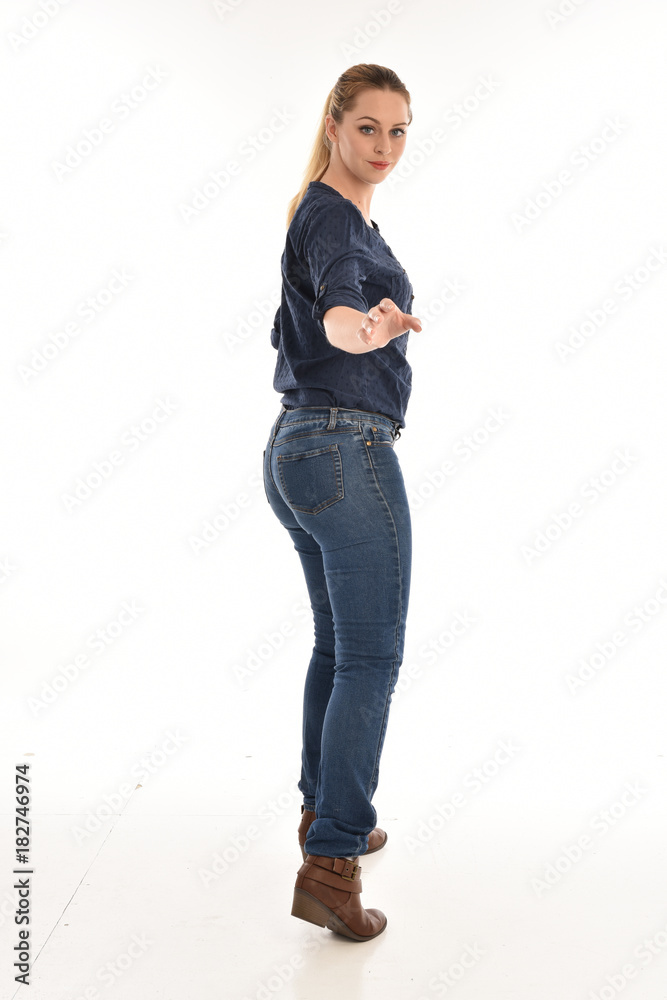 Full length portrait of a girl wearing simple blue shirt and jeans, standing pose facing away on a white background. Full length portrait of a girl wearing simple blue shirt and jeans, standing pose facing away on a white background.