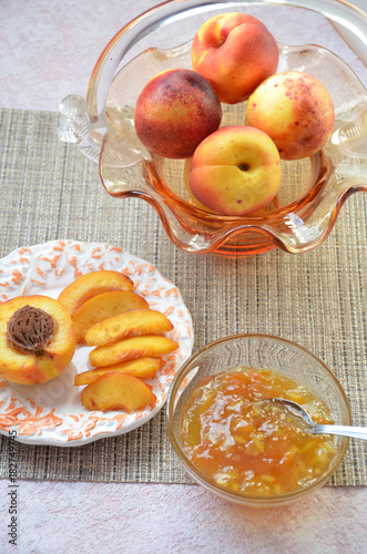 Bowl of peach jam on on a table, cut peach on a plate, of a beautiful vase in the shape of a basket background