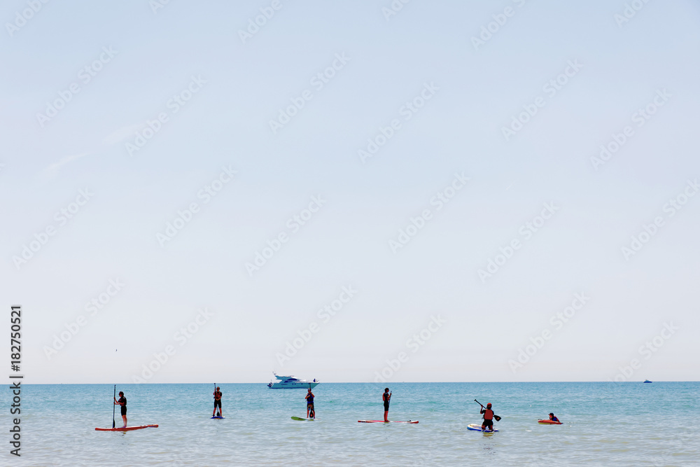 People practice Stand Up Paddleboarding outside the Brighton beach