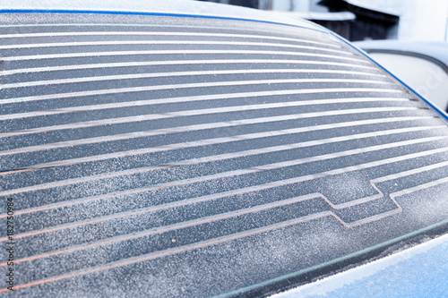 Rear car window covered with frost, warmed defroster. photo