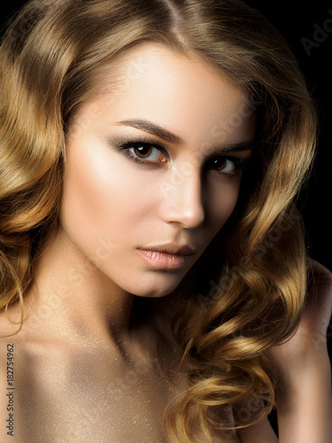 Beauty portrait of young woman with golden makeup