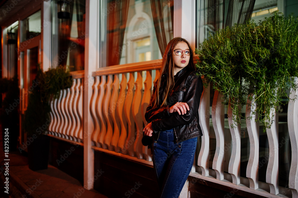 Night portrait of girl model wear on glasses, jeans and leather jacket, with backpack , against city streets.