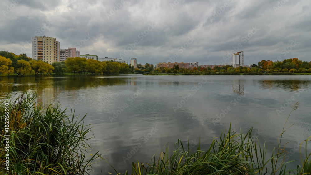 cityscape. The residential city quarter on the shore of the lake in the autumn under a cloudy sky. view from the coast