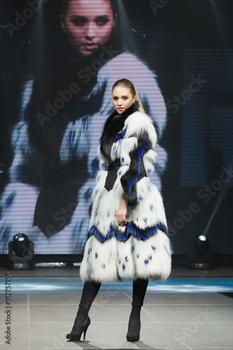 Canvastavla Beautiful fashion model  walks on runway in fur coat with online screen on backg