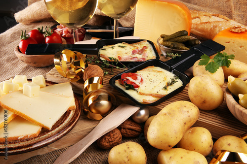Photography Delicious traditional Swiss melted raclette cheese on diced boiled or baked potato served in individual skillets