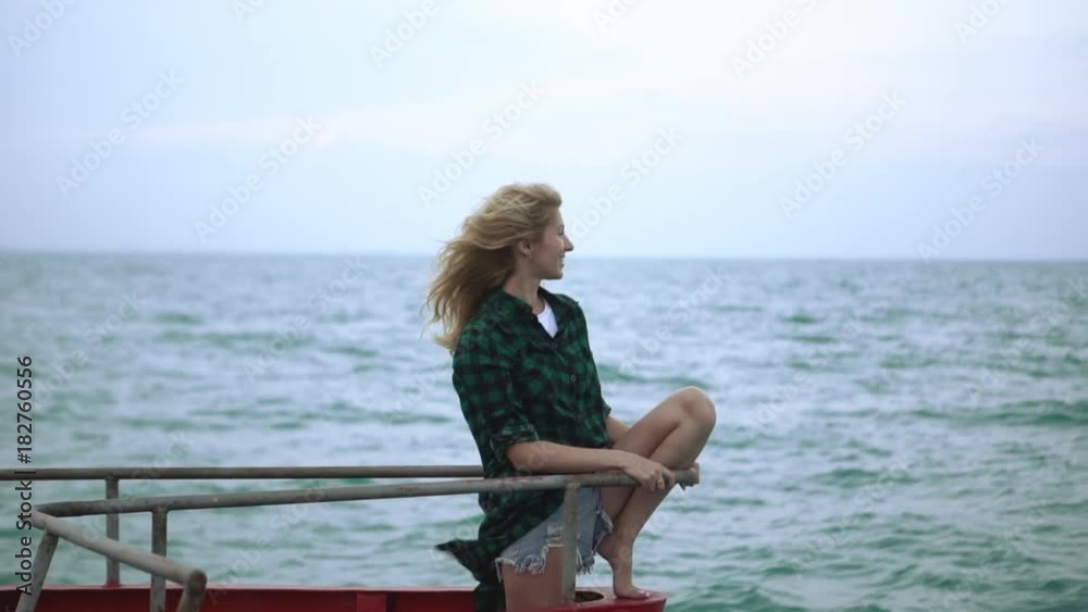 Young woman with long white hair sitting on a boat staring at horizon with smile Young woman with long white hair sitting on a boat staring at horizon with smile