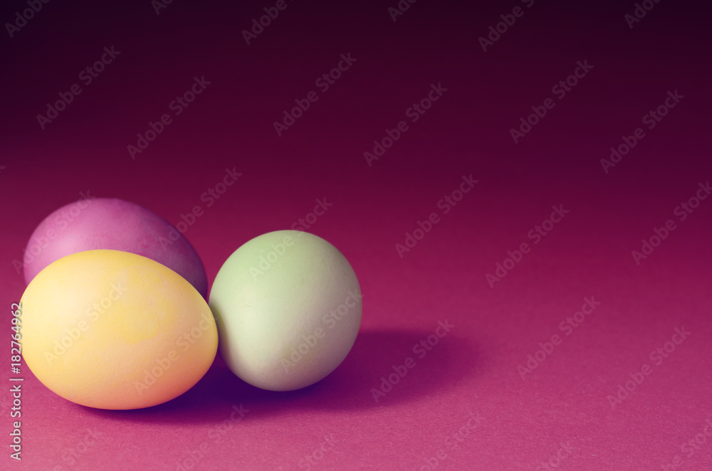 Trendy photo of Three multi colored easter eggs on a dark purple background. Trendy photo of Three multi colored easter eggs on a dark purple background.