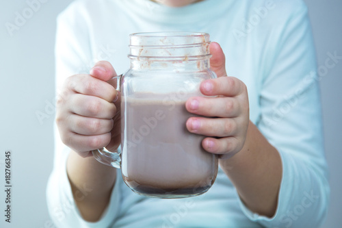 Cute caucasian boy holds a glass jar of cocoa