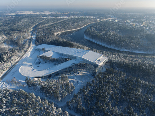 Winter aerial view of Snow Arena surrounded with snowy pine tree forest. Revealing Druskininkai city, Lithuania. photo