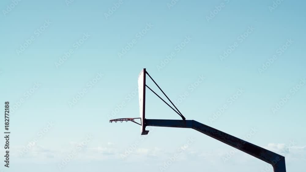 Old basketball board with basket hoop on blue sky background, side view. Sport, recreation outside concept. Old basketball board with basket hoop on blue sky background, side view. Sport, recreation outside concept.