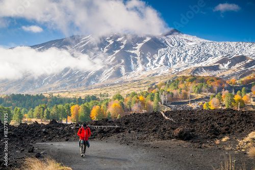 Mount Etna, Italy: panorama of the northern side of the volcano and a hiker walking on a lavic pathway photo