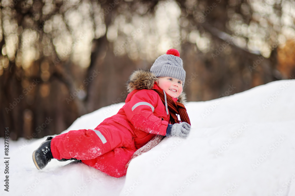 Little boy in red winter clothes having fun with fresh snow
