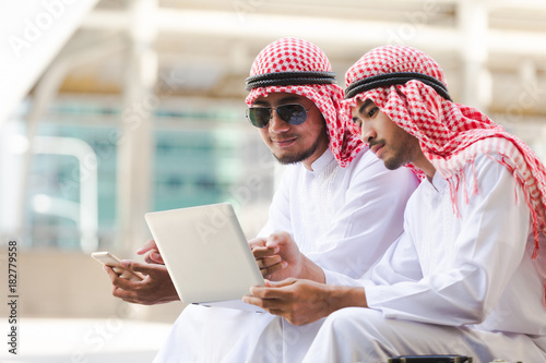 Arab business man call phone working on taplet in the city