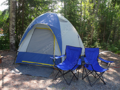 Gray and blue dome camping tent with two blue chairs on campsite