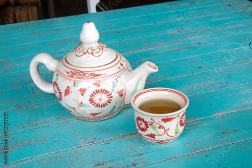 Hot tea in a teapot and a cup on blue wooden table. © Zinsmute