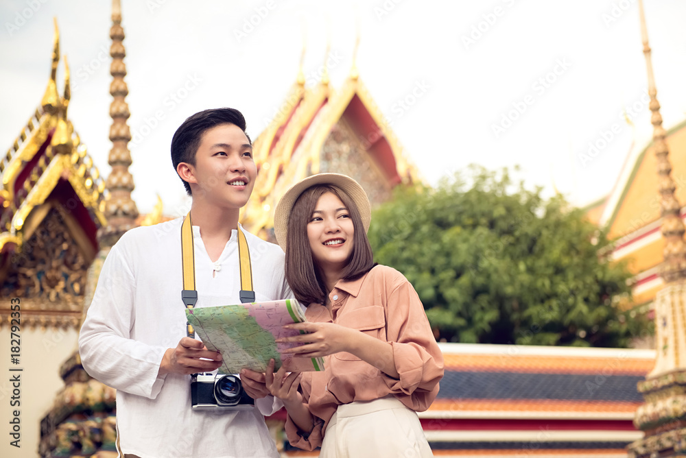 Fototapeta premium Asian couple tourists visiting Thai temple, Wat Pho, in Bangkok Thailand