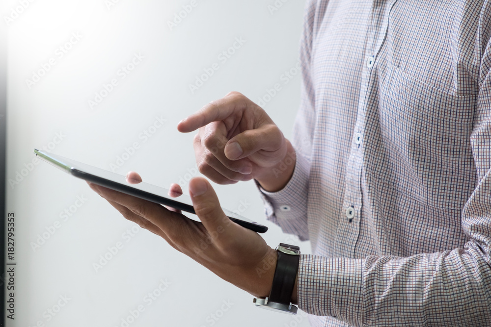 Modern businessman with tablet computer reading news and work report document at morning in office.
