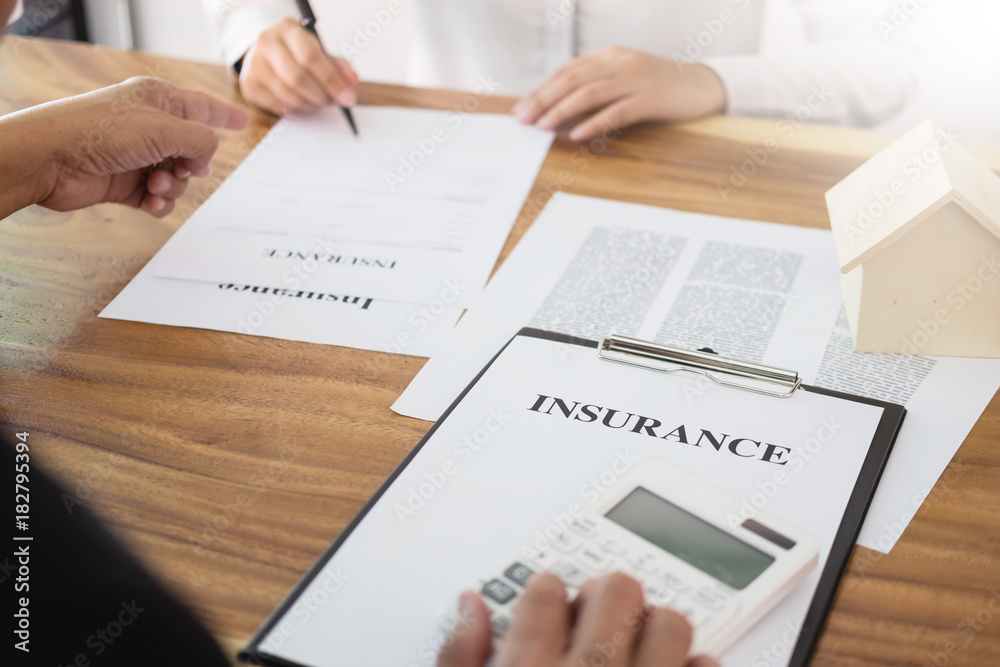 Man signing a car insurance policy, the agent is holding the document. Man signing a car insurance policy, the agent is holding the document.