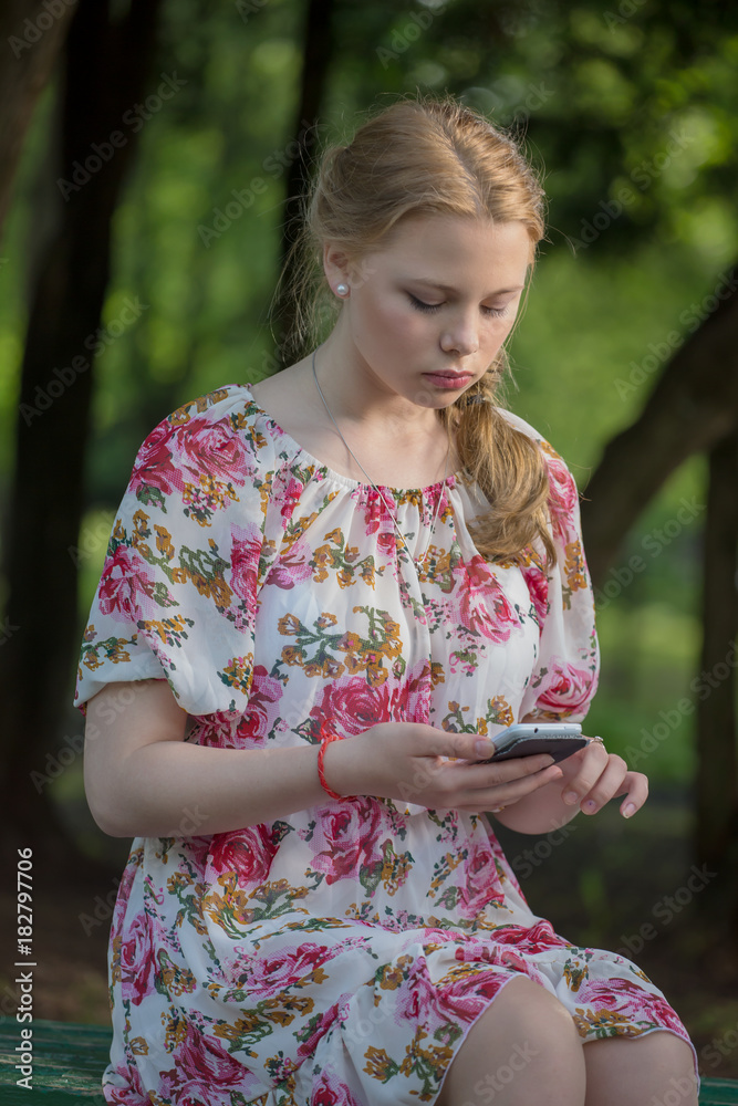 Sad pretty girl sitting on a Park bench and wants to call Sad pretty girl sitting on a Park bench and wants to call